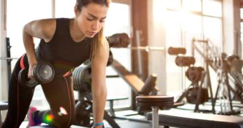 Fitness girl lifting dumbbell in the morning. Using multigym equipment